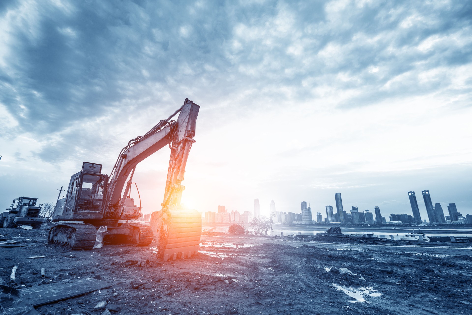excavator in construction site on sunset sky background